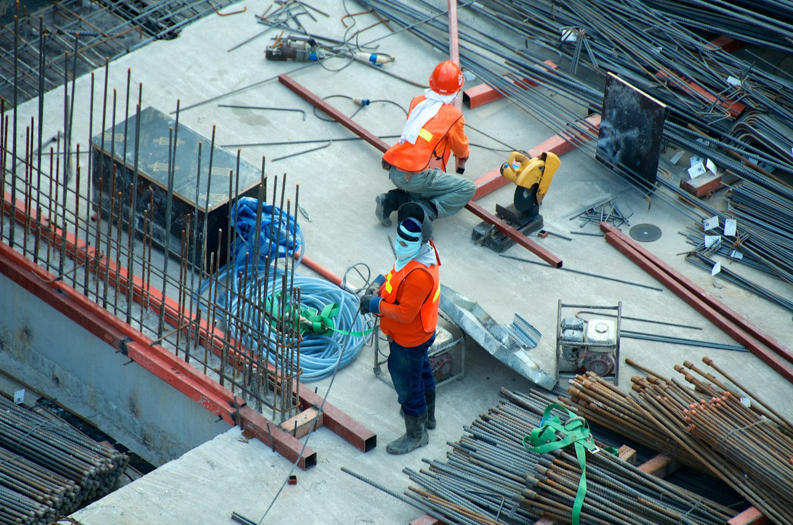 Construction workers in safety gear on a rebar deck